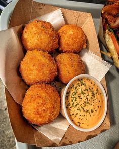 some food is sitting on a tray next to a sandwich and dipping sauce in a bowl