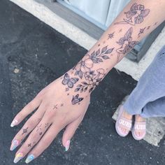 a woman's hand with flowers and stars tattooed on her left arm, next to a door