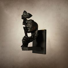 a sculpture of a dog holding a branch in its mouth on a shelf against a wall