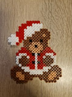 a cross stitch christmas ornament with a teddy bear wearing a santa claus hat