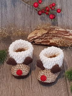 crocheted baby booties with red nose on wooden floor next to christmas decorations