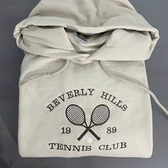 Vintage Beverly Hills Hoodie | Tennis Club Athletics Hoodie, custom embroidery design, vintage style athletic hoodie; gift for her; gift for him crewneckplease message me if you need any customization! Sizes: S, M, L, XL, 2XL, 3XL8 oz., 50% cotton, 50% polyesterSafety Orange is compliant with ANSI - ISEA 107 High Visibility Standards1x1 ribbed collar, cuffs and waistband with spandexDouble-needle stitching throughoutPill-resistant air jet yarnSet-in sleevesColors of the text & design/sweater may Tennis Hoodie Designs, Club Hoodie Design, Country Club Merch, School Hoodies Design, Tennis Merch, Tennis Sweater, Athletic Hoodie, Vintage Tennis, Tennis Club