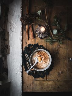 a bowl filled with food sitting on top of a wooden table next to a candle