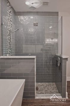 a walk in shower sitting next to a white bath tub under a light fixture on the ceiling