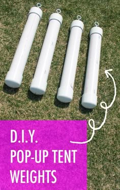 four white cylinders sitting on top of a green field next to a purple sign that says diy pop - up tent weights