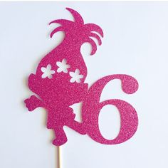 a pink cake topper with the number six on it