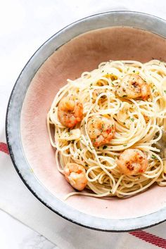 a bowl filled with pasta and shrimp on top of a table