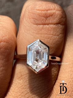 a woman's hand with a ring on it and an emerald stone in the middle