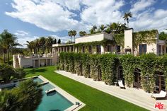 the house is surrounded by greenery and has a swimming pool in front of it