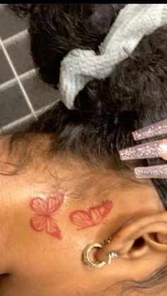 a close up of a person with tattoos on their head and behind her ear,