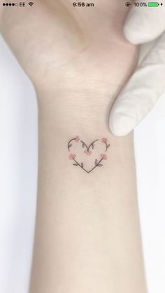 a small tattoo on the wrist of a woman's left arm with pink flowers