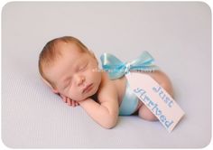 a baby wearing a blue diaper with a name tag laying on it's side