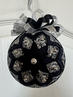 a black and white ornament hanging from a door with silver bows on it