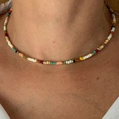 a woman wearing a necklace with multicolored beads on the neck and bottom of her chest