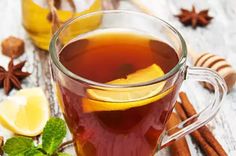 a glass cup filled with tea next to cinnamons and star anise