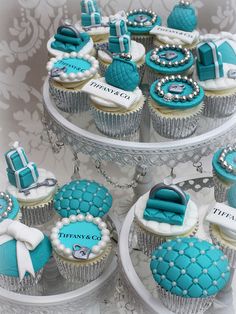 cupcakes decorated with blue and white frosting are displayed on three tiered plates