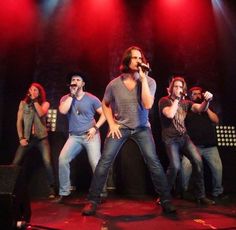 a group of men standing on top of a stage with microphones in their hands