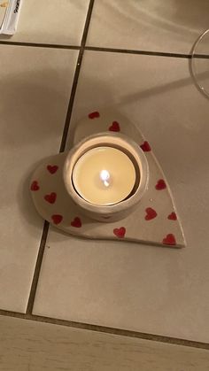 a lit candle sitting on top of a tile floor