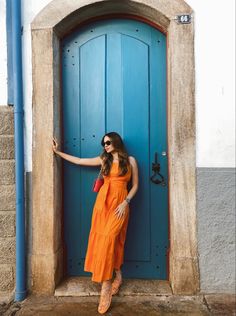 a woman standing in front of a blue door with her hand on the side of it