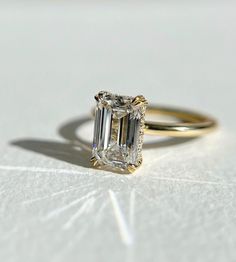 a diamond ring sitting on top of a white surface with a shadow coming from it