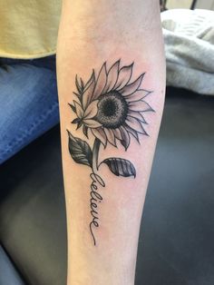 a black and white photo of a sunflower tattoo on the left leg with words written in cursive writing