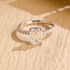 an engagement ring with a square cut diamond on the side and pave set shoulders