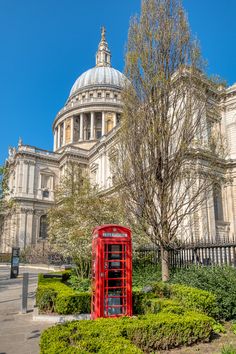 a red phone booth sitting in front of a building with a dome on the top