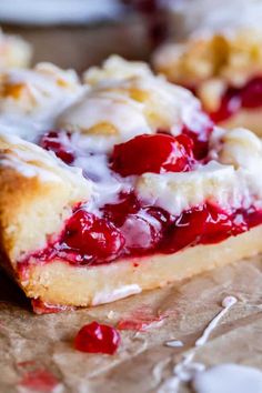 a close up of a piece of cake with cherries and icing on it