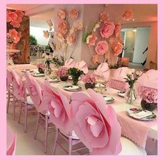 a long table with pink chairs and flowers on it