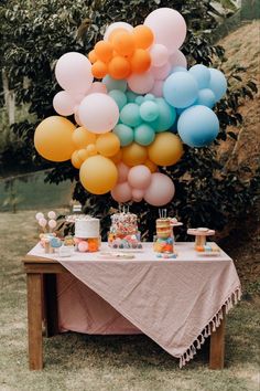 a table topped with lots of balloons and cake