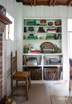 the bookshelf is filled with lots of books and wicker baskets on it