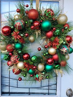 a wreath with christmas ornaments hanging on the front door