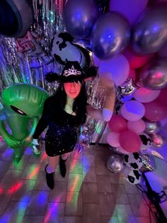 a woman in a witch costume standing next to balloons