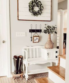 a white bench sitting in front of a doorway with a wreath on the wall above it