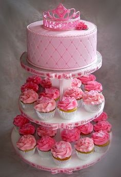 a three tiered cake with pink cupcakes on it