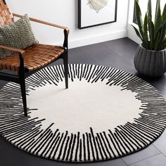 a black and white rug in a living room with a chair, potted plant and pictures on the wall