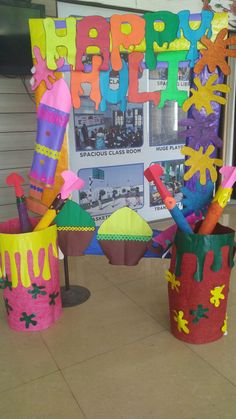 three buckets that have been decorated with different colors and shapes, sitting on the floor in front of a poster