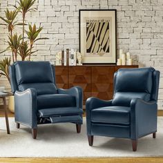 two blue leather chairs in front of a brick wall with a potted plant next to it