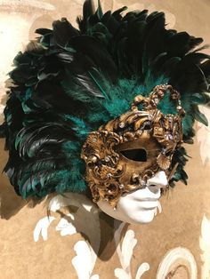 This masquerade mask for man and woman belongs to our collection of feathers' masks. These masks have a crown of black and green marine real feathers. It is perfect for any masquerade party, Halloween costume, pro or event in Venice or elsewhere during Carnival. This mask can be gently bent to form to your face and ties in the back with two soft matching ribbons. Since the mask is handmade, your mask could be lightly different from the one in the picture. This mask is made on paper mache,with cr Green Masks For Carnival Costume Party, Green Carnival Masks And Prosthetics, Green Masks And Prosthetics For Carnival Costume Party, Carnival Feather Eye Mask, Feathered Masks For Carnival Costume Party, Feather Masks For Carnival Costume Party, Green Masks For Mardi Gras Carnival, Green Costume Mask For Carnival, Green Carnival Costume Mask