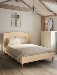 a bed sitting in a bedroom next to a white dresser and lamp on top of a hard wood floor