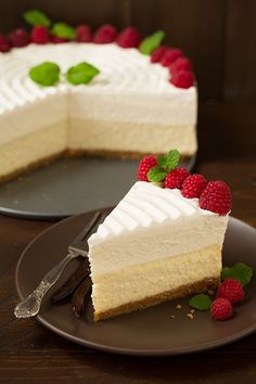 a piece of cake with white frosting and raspberries on the top is sitting on a plate