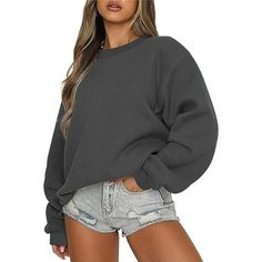 a woman wearing a grey sweatshirt and denim shorts