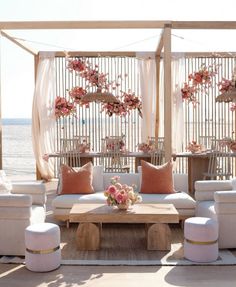 an outdoor seating area with white couches and pink flowers