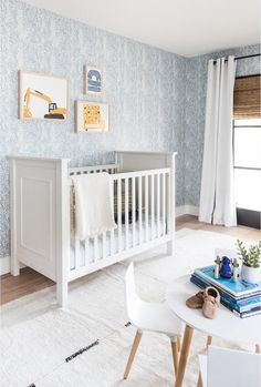 a baby's room with blue wallpaper, white furniture and pictures on the walls