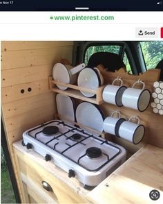 a stove top oven sitting in the back of a truck with plates and cups on it