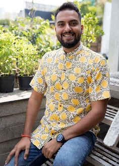 a man sitting on top of a wooden bench next to potted plants in front of him