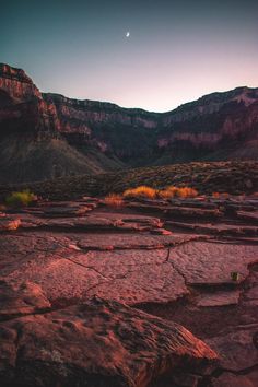 the sun is setting over some rocks and mountains