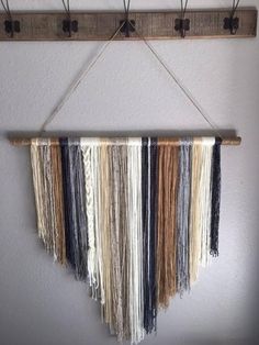 a wall hanging with several different colors of yarn on it and two hooks attached to the wall