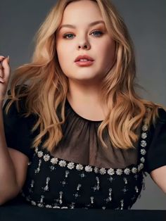 a woman with blonde hair and blue eyes posing for a magazine cover photo in black dress