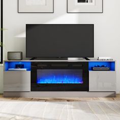 an entertainment center with a television and blue flames on the side, in front of two framed pictures